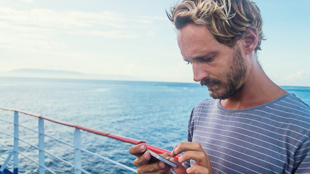 Male using his phone on board